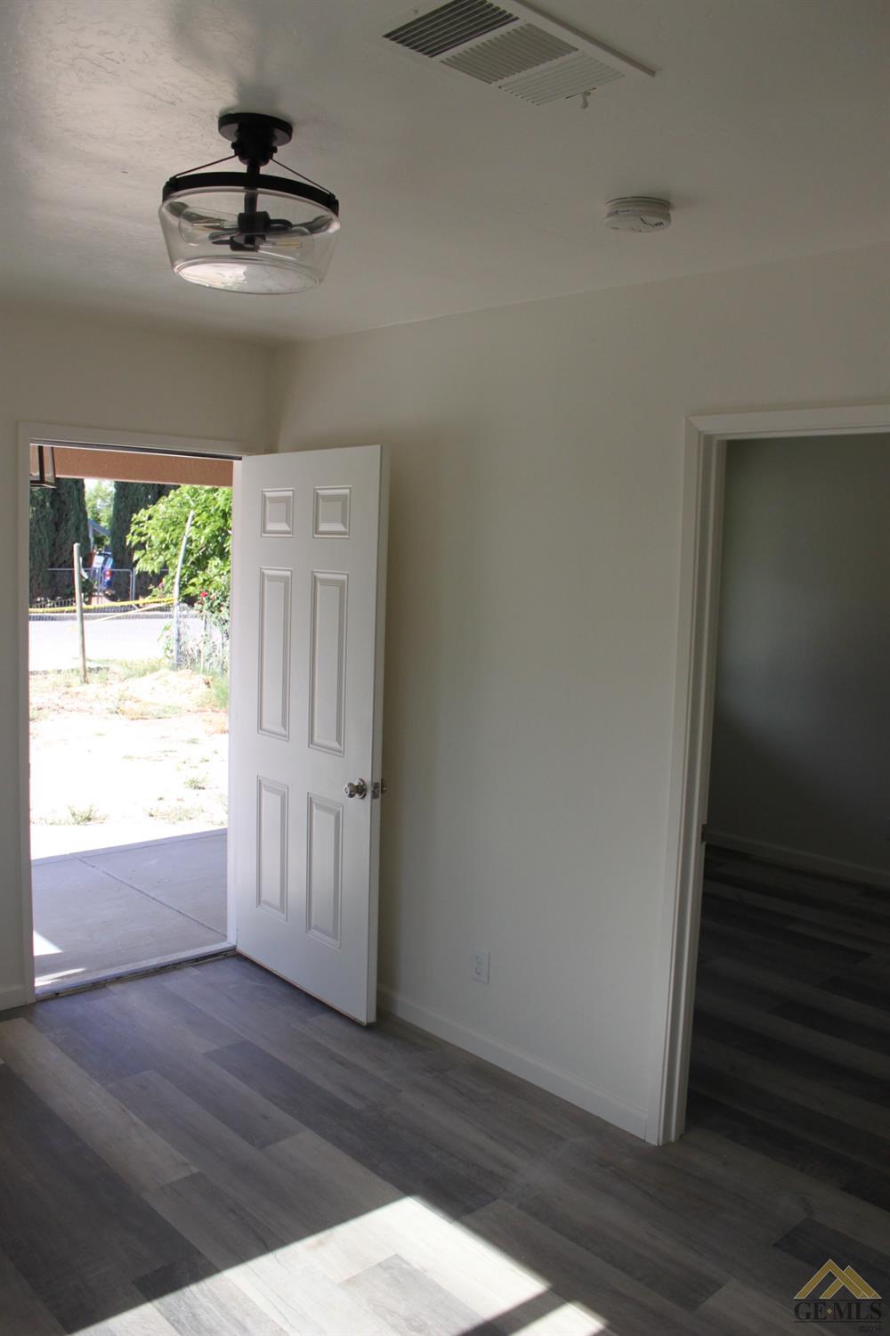 Undisclosed Address Wasco, CA 93280 - Photo 6 of 26 a view of an empty room with wooden floor and a window