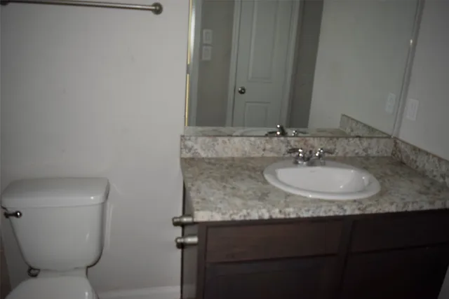 a bathroom with a granite countertop sink a toilet and a mirror