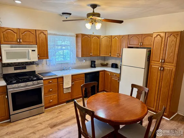 a kitchen with stainless steel appliances a stove a refrigerator a sink a dining table and chairs