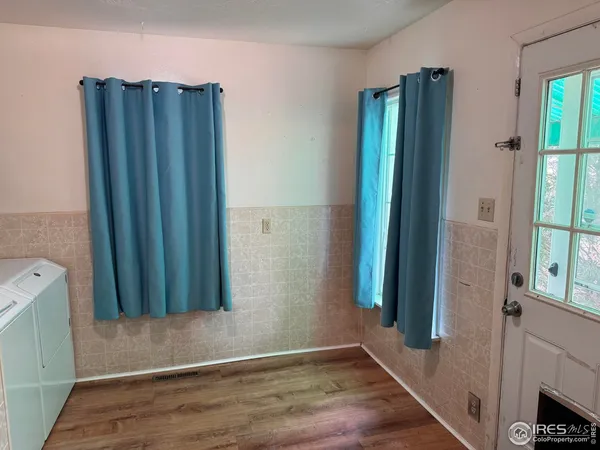 a view of a hallway with wooden floor and a bathroom