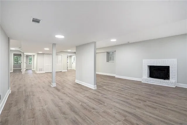 a view of an empty room with wooden floor fireplace and a window