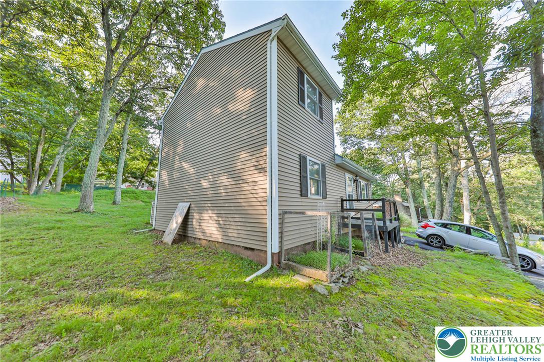 2114 Lakeview Road Bushkill, PA 18324 - Photo 66 of 83 Mature trees surround a multi-level home featuring neutral siding and a rear wooden deck.