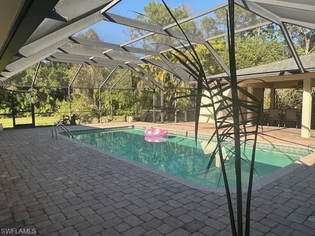 1261 Pine Ridge Road Naples, FL 34108 - Photo 2 of 13 Swimming pool featuring a sunroom, a patio area, glass enclosure, and view of scattered trees