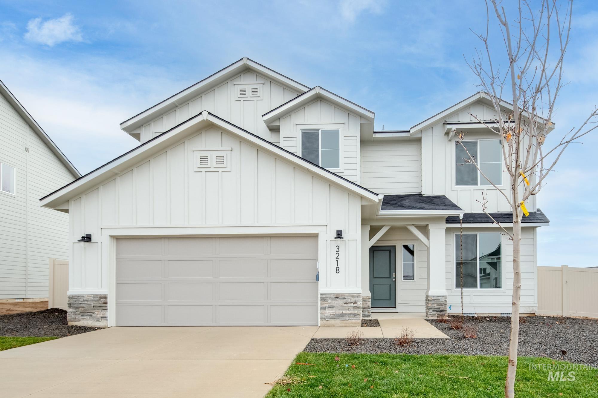 View of front of home featuring board and batten siding, stone siding, concrete driveway, a shingled roof, and an attached garage