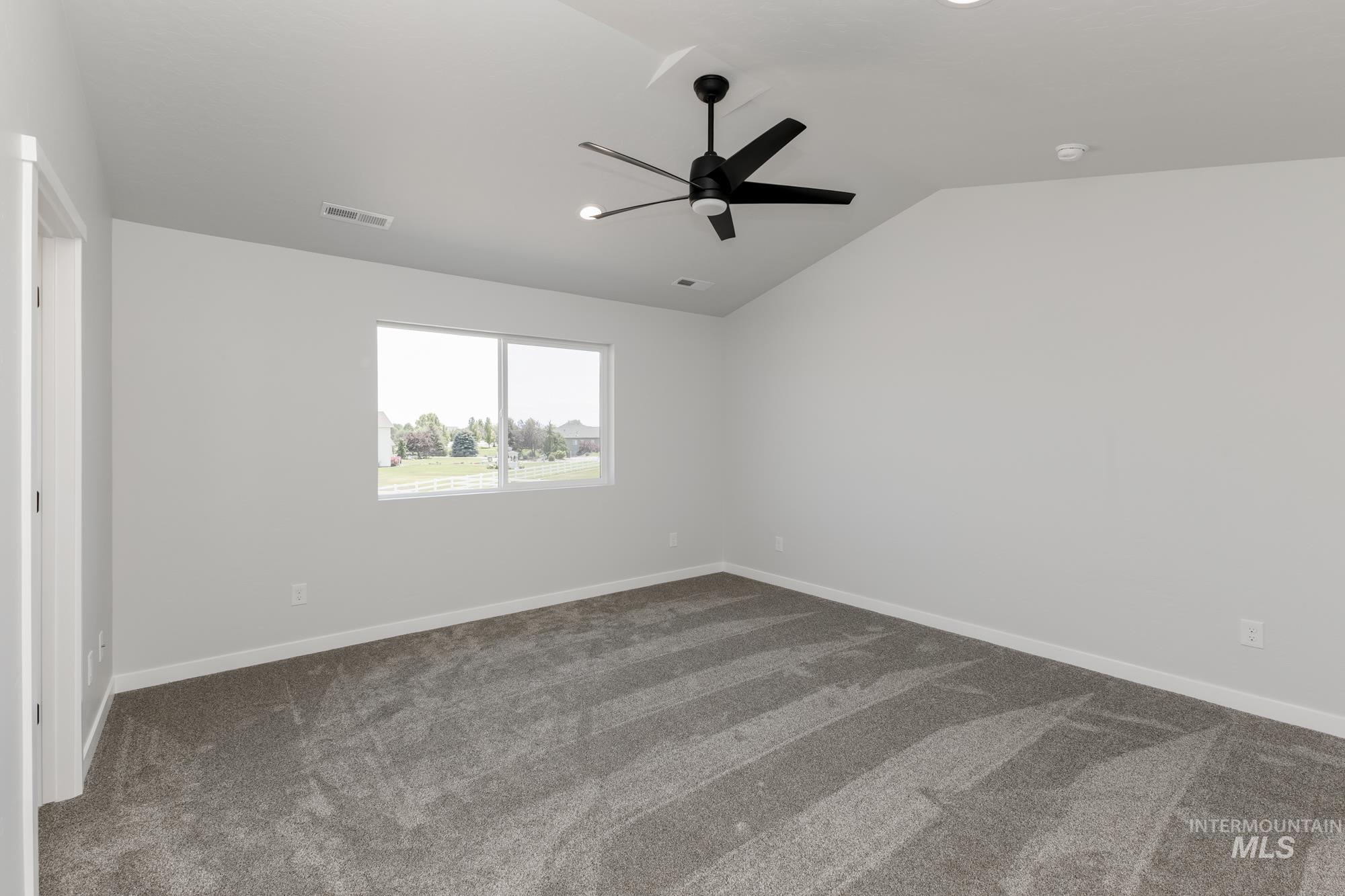 3218 North Waterbrook Way Star, ID 83669 - Photo 21 of 27 Empty room with dark carpet, vaulted ceiling, and ceiling fan