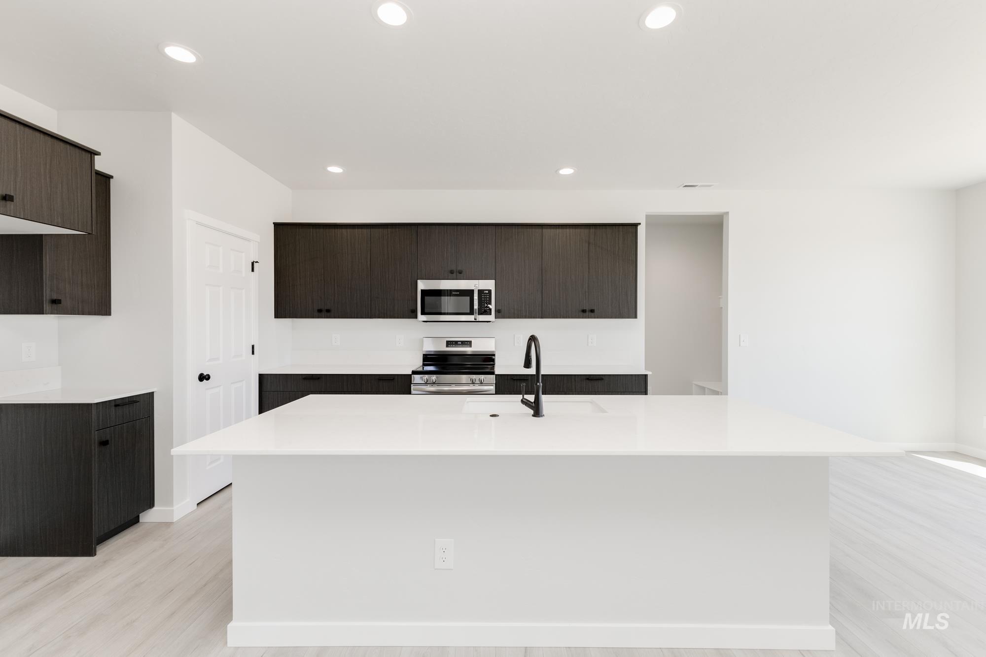 3218 North Waterbrook Way Star, ID 83669 - Photo 3 of 27 Kitchen featuring stainless steel appliances, a center island with sink, dark brown cabinetry, light wood-style floors, and recessed lighting