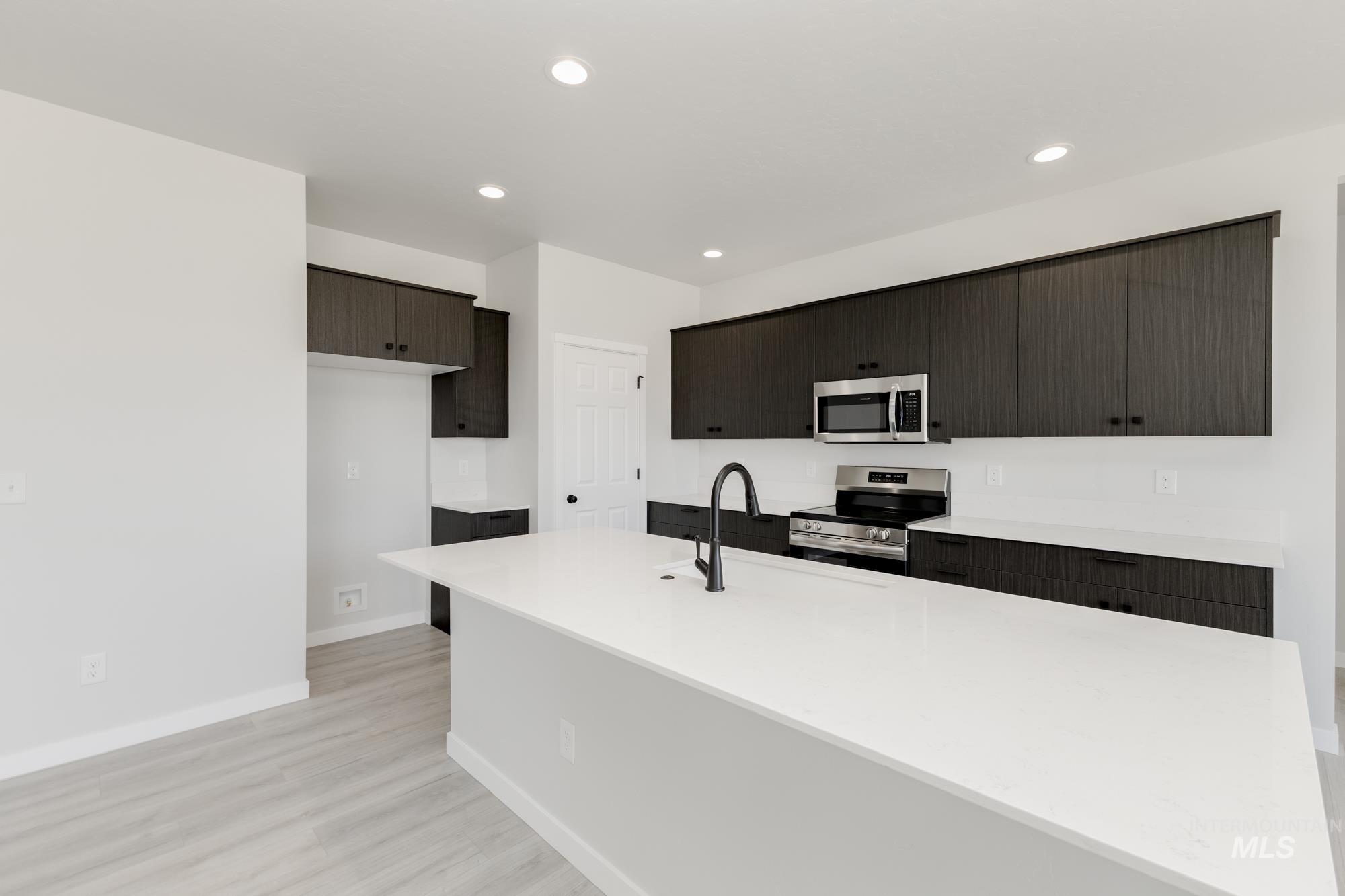 3218 North Waterbrook Way Star, ID 83669 - Photo 4 of 27 Kitchen with appliances with stainless steel finishes, a kitchen island with sink, light wood-style flooring, light stone countertops, and recessed lighting