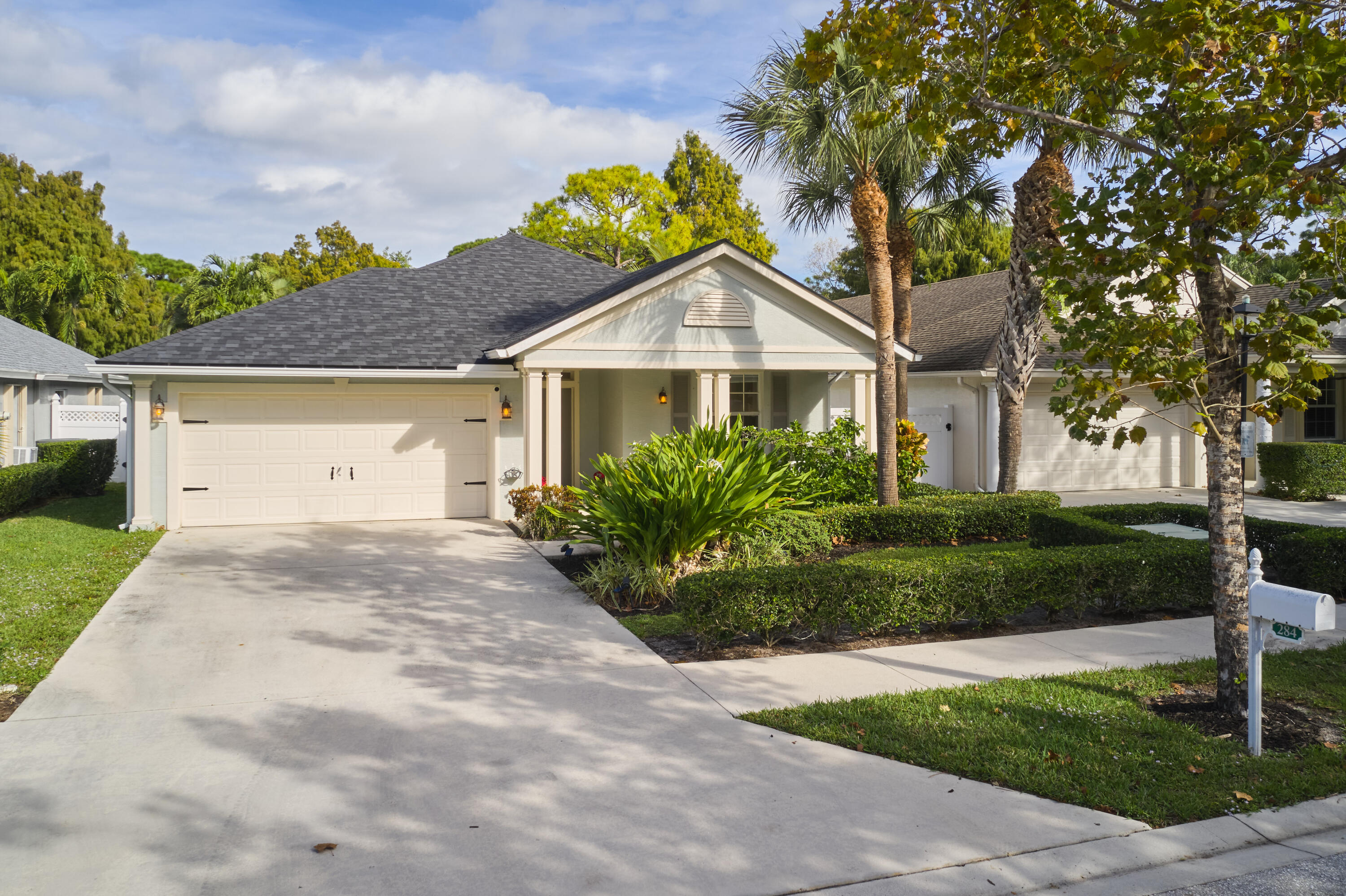 a front view of a house with a garden and trees