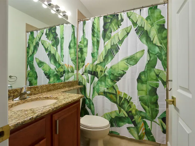 a bathroom with a granite countertop sink and a toilet
