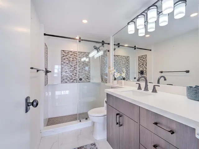 a bathroom with a double vanity sink toilet mirror and shower