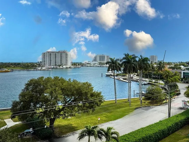 a view of a lake with a yard and large trees