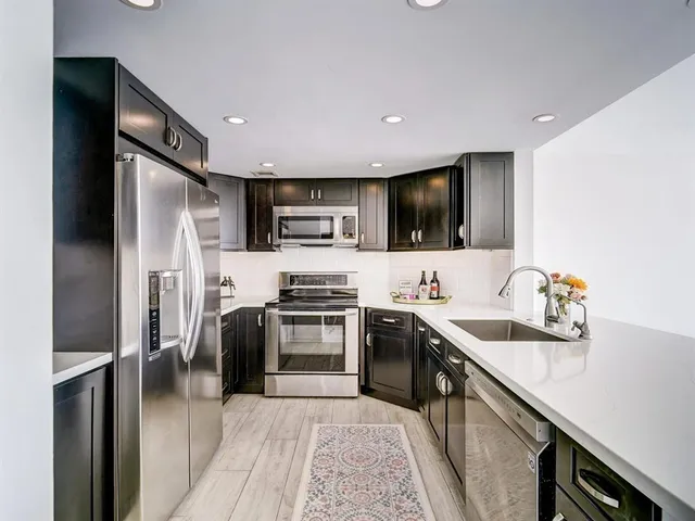 a kitchen with stainless steel appliances sink stove refrigerator and cabinets