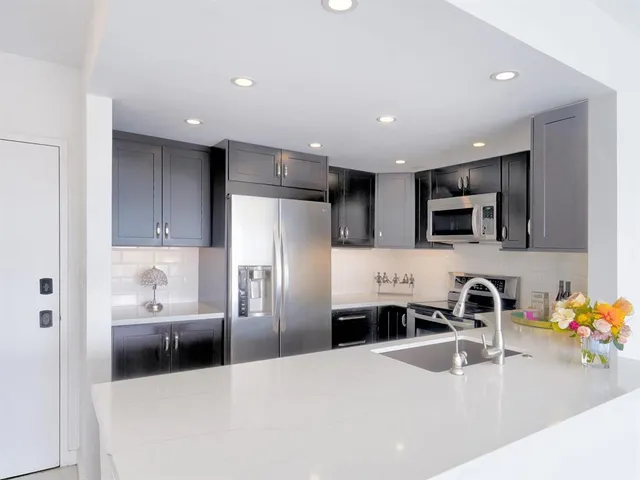 a kitchen with stainless steel appliances a sink a microwave a refrigerator and cabinets