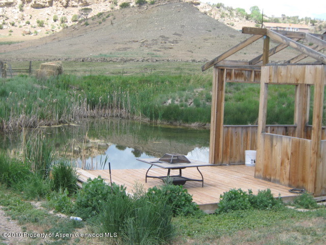 2920 County Road 233 Rifle, CO 81650 - Photo 3 of 13 a view of a lake with a garden and a wooden bench