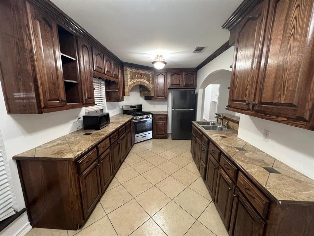 6707 Elam Road Dallas, TX 75217 - Photo 2 of 18 a kitchen with granite countertop stainless steel appliances a sink stove top oven and cabinets