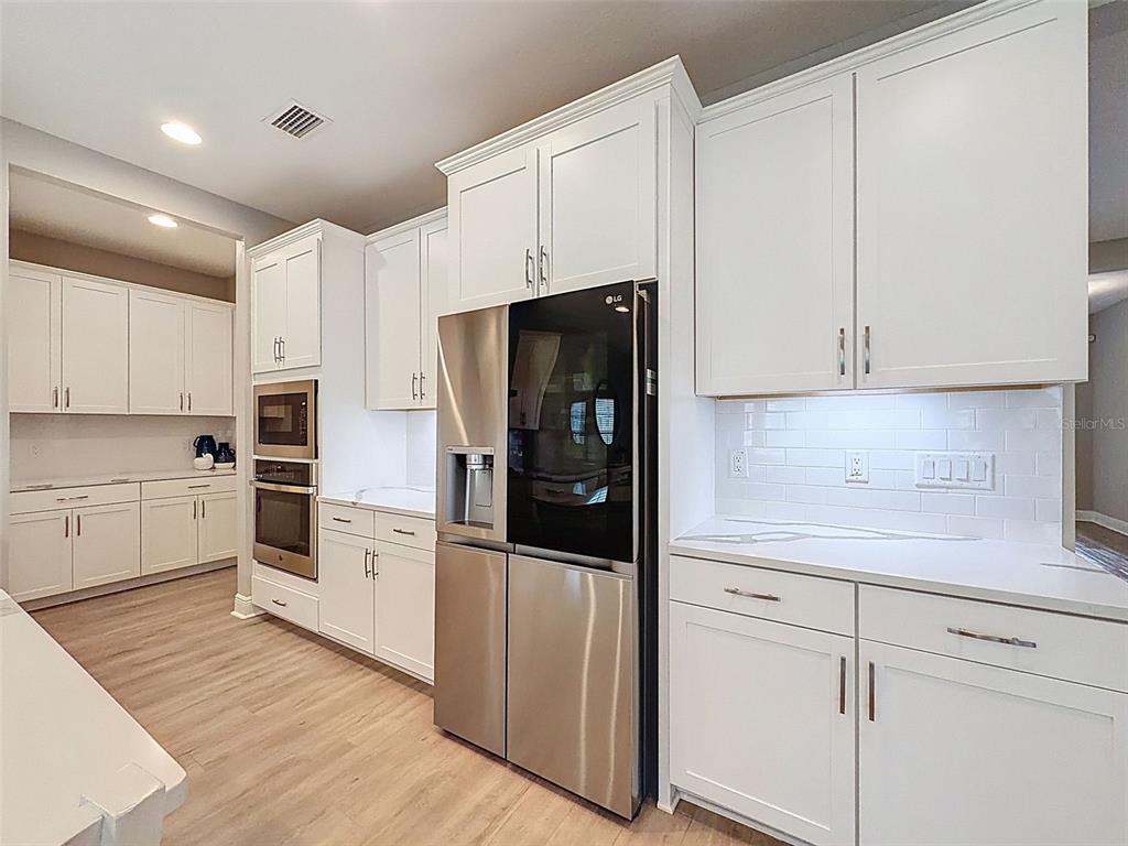 4312 Burdick Loop Odessa, FL 33556 - Photo 13 of 55 a kitchen with white cabinets and stainless steel appliances