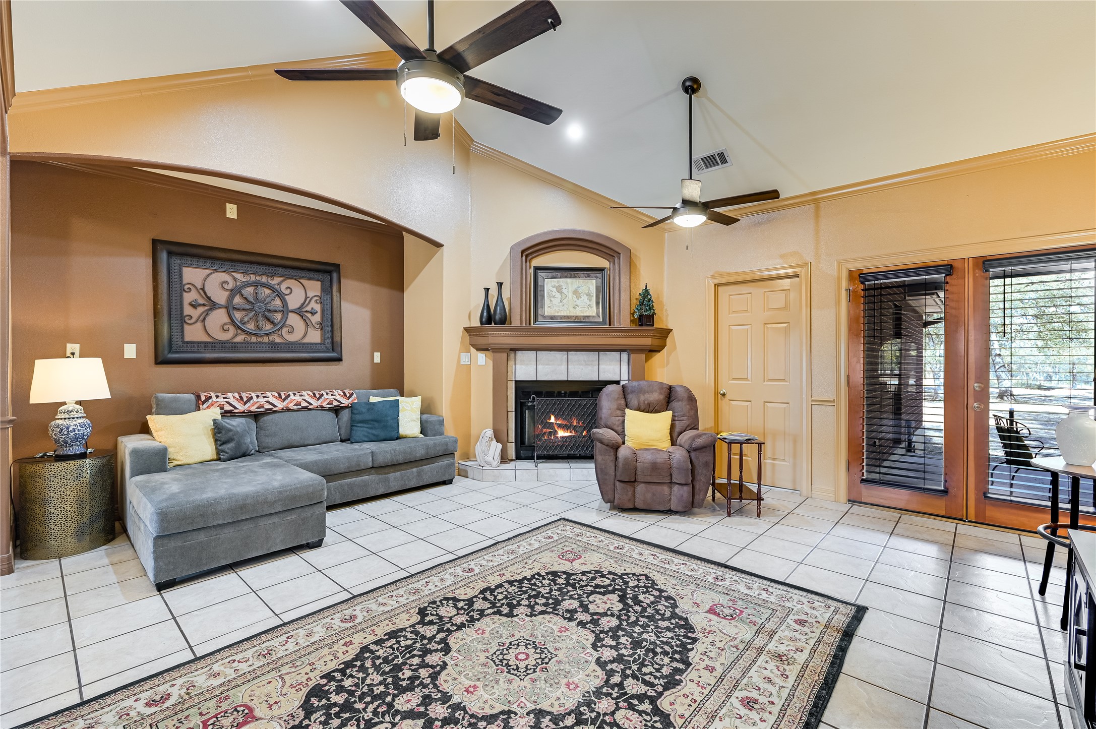 486 Westwood Road Lockhart, TX 78644 - Photo 5 of 29 Living area with crown molding, lofted ceiling, a tile fireplace, light tile floors, and large amount of natural light