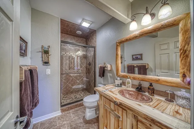a bathroom with a granite countertop sink a toilet a mirror and shower