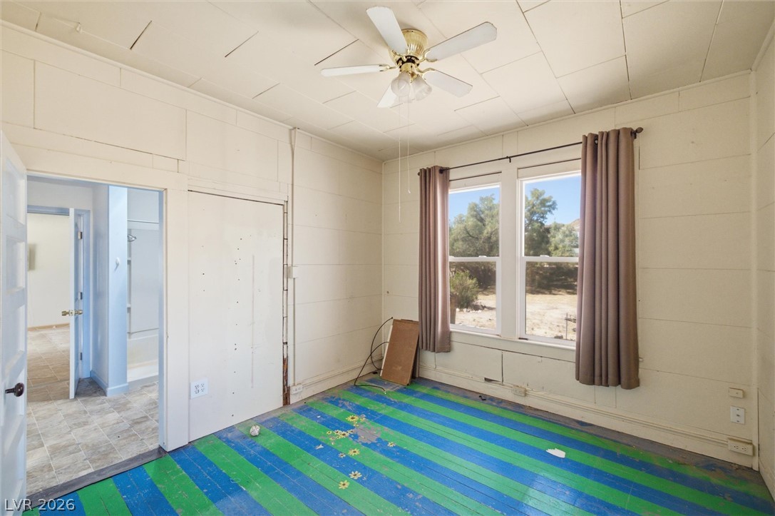 405 Main Street Beatty, NV 89003 - Photo 5 of 28 A vibrant blue and green striped floor anchors this cozy bedroom, offering a distinctive, playful aesthetic.