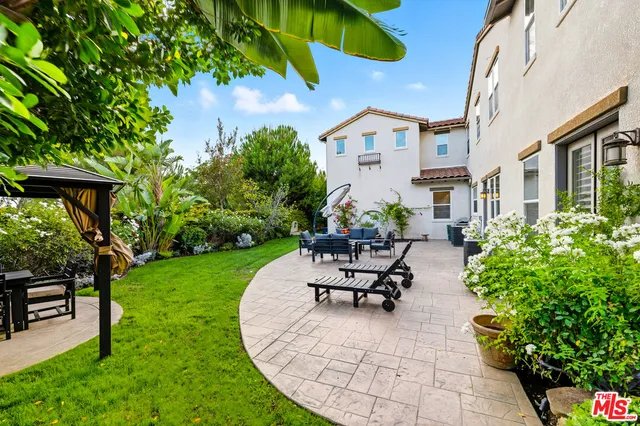 a view of a patio with table and chairs potted plants and a bench