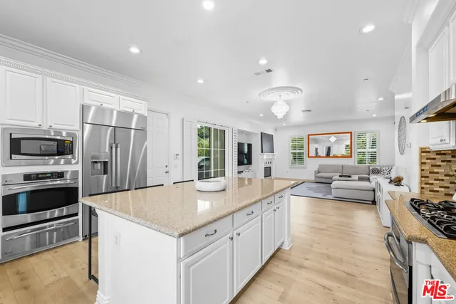 a large kitchen with kitchen island a large counter top space stainless steel appliances and cabinets