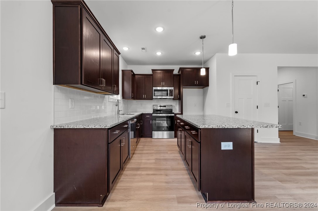2902 Calloway (lot 1) Road Raeford, NC 28376 - Photo 21 of 44 a large kitchen with stainless steel appliances kitchen island a large counter top a stove a refrigerator cabinets a fireplace and a wooden floor