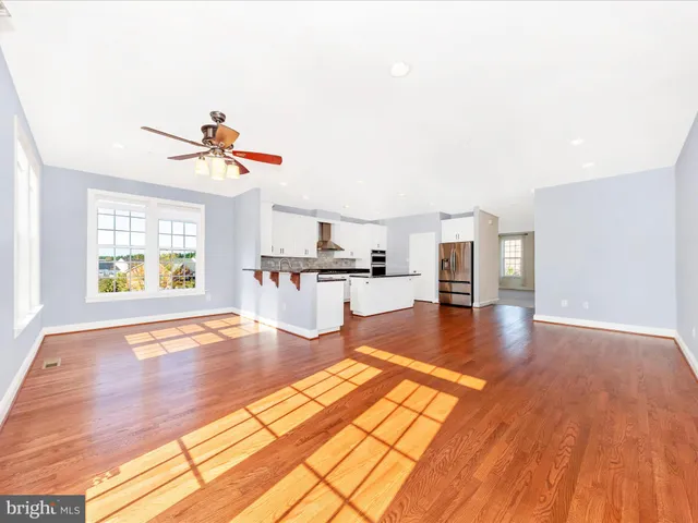 a kitchen with stainless steel appliances granite countertop a stove top oven a sink and white cabinets with wooden floor