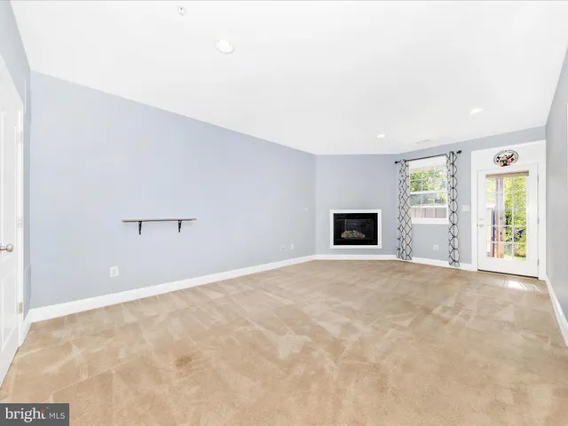 a view of an empty room with a window and a kitchen