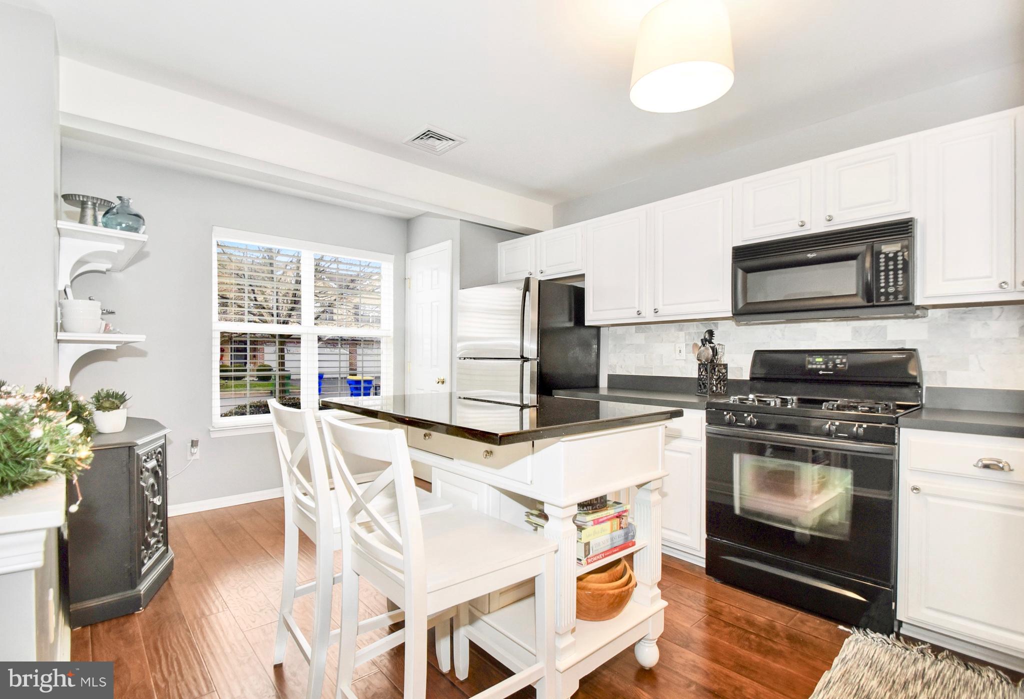 102 Peregrine Lane Hummelstown, PA 17036 - Photo 5 of 28 a kitchen with stainless steel appliances granite countertop a stove top oven a sink dishwasher a dining table and chairs with wooden floor