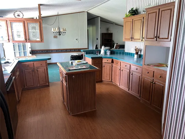 a kitchen with stainless steel appliances granite countertop a stove a sink dishwasher and a refrigerator with wooden floor