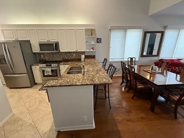 a kitchen with granite countertop a table chairs microwave and sink