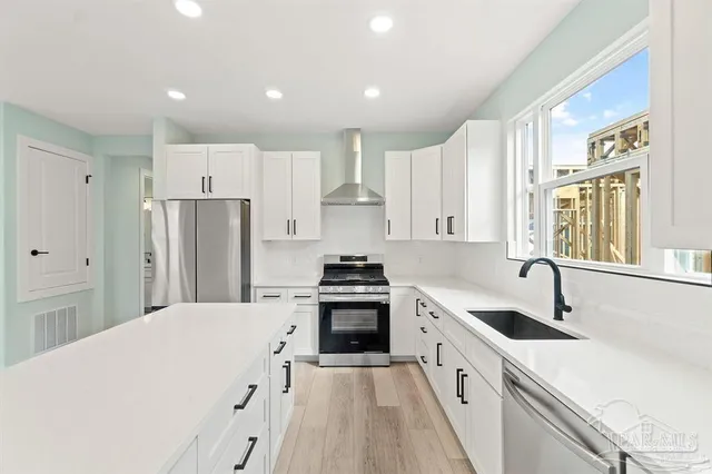 a kitchen with kitchen island white cabinets a sink a stove a refrigerator and a stove