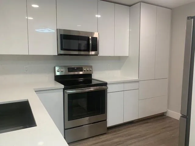 a kitchen with stainless steel appliances granite countertop a stove a microwave and a white cabinets