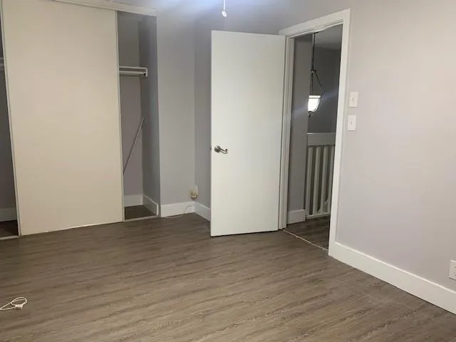 a view of an empty room with wooden floor and closet