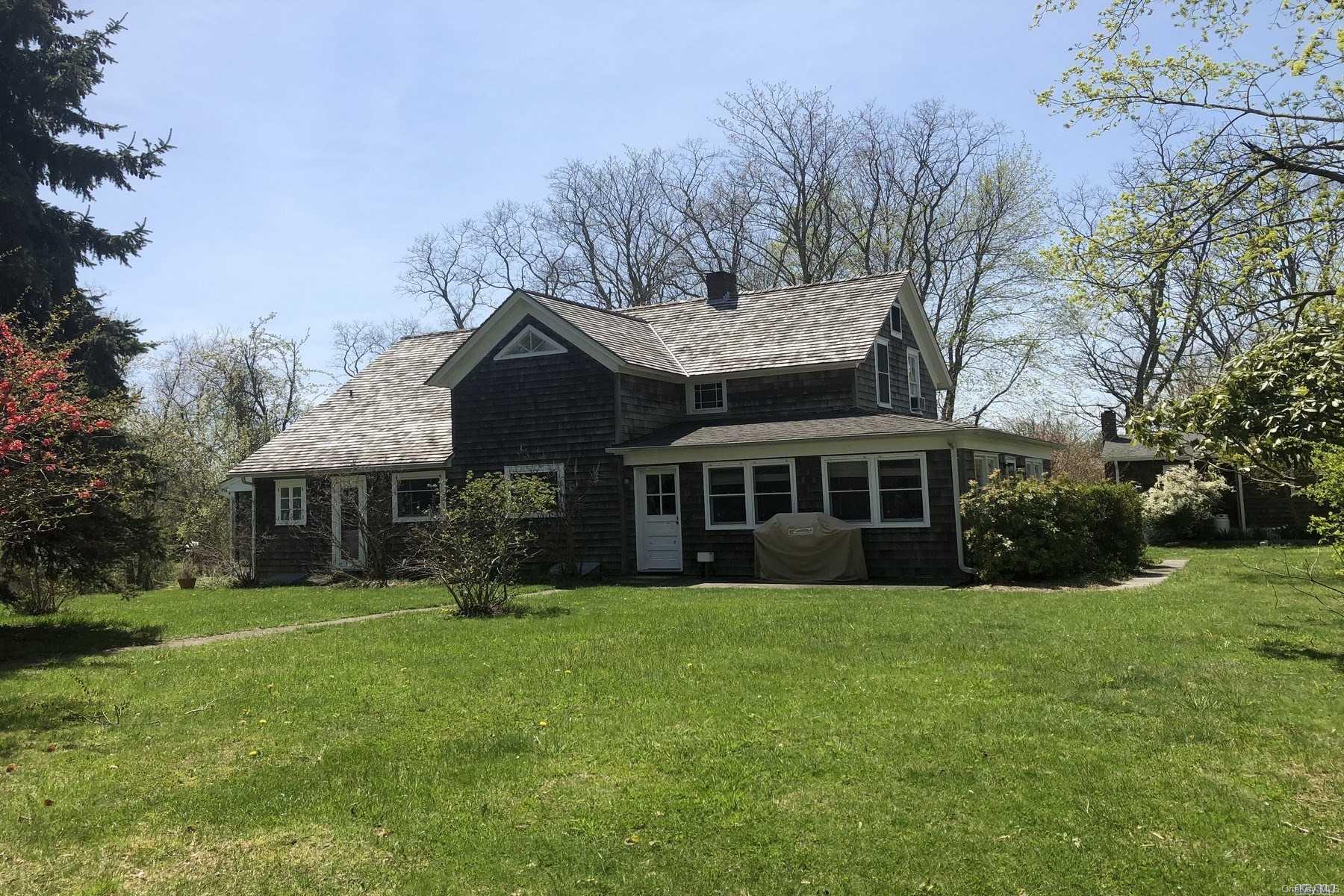 a view of a house next to a big yard and large trees
