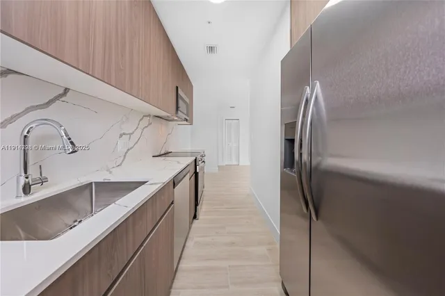 a kitchen with kitchen island granite countertop a sink and refrigerator
