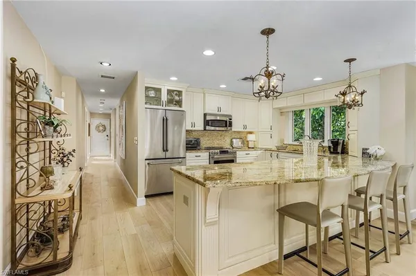 a kitchen with stainless steel appliances kitchen island granite countertop a refrigerator and a view of living room