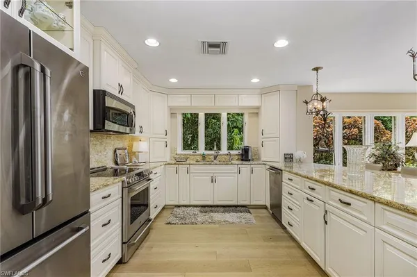 a large kitchen with stainless steel appliances granite countertop a stove and a sink