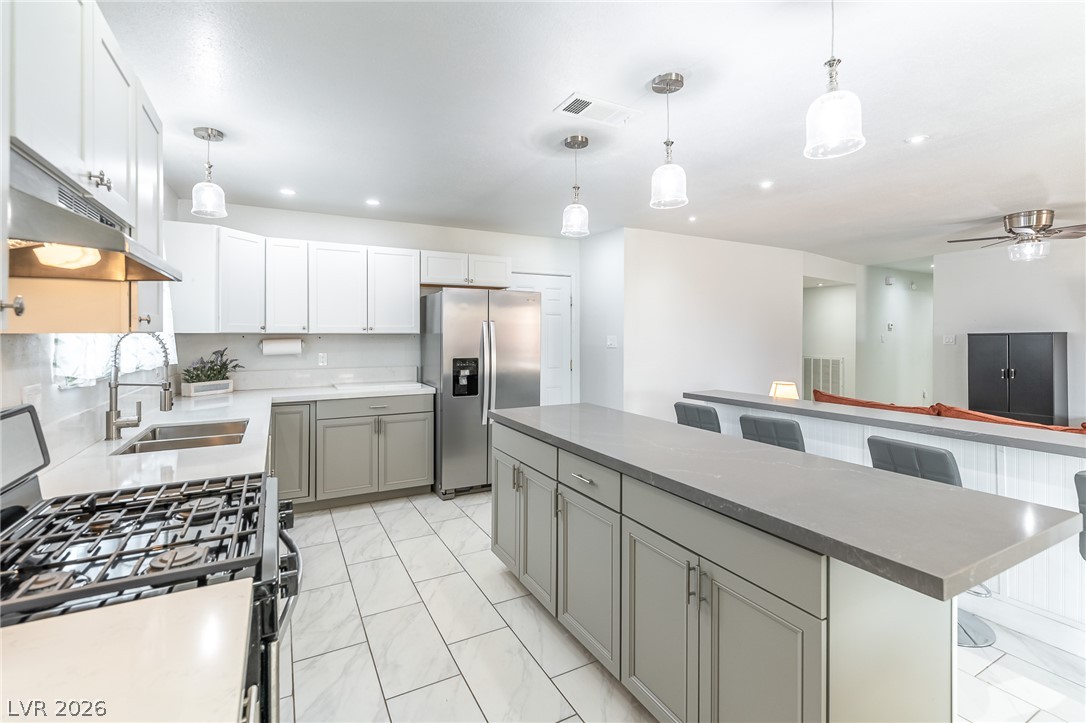 105 South Cimarron Road Las Vegas, NV 89145 - Photo 13 of 28 Polished tile flooring and quartz counters anchor this modern, open kitchen design.