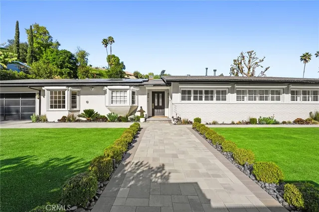 a front view of a house with a yard and potted plants