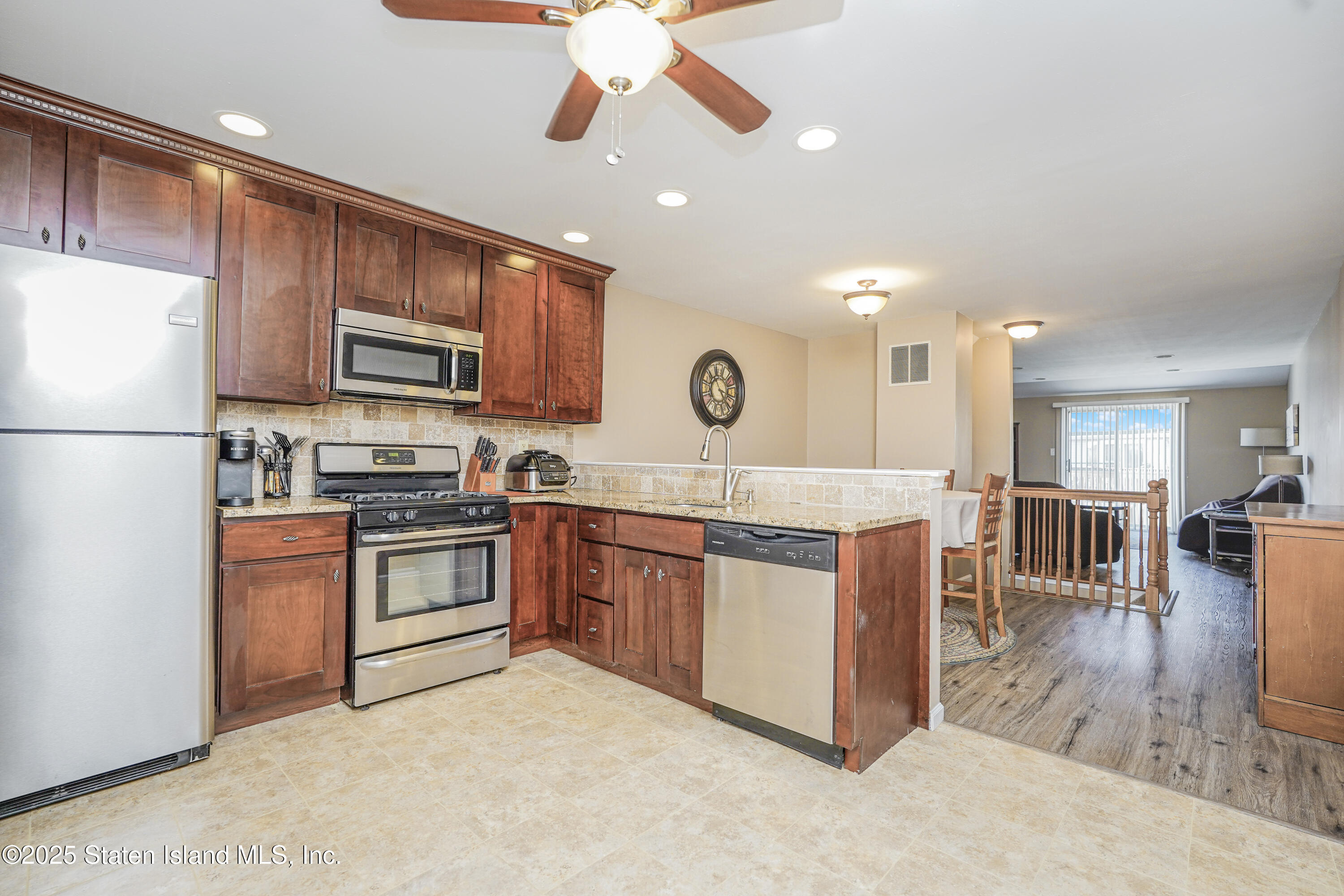 120 Pembrook Loop Staten Island, NY 10309 - Photo 10 of 24 a kitchen with stainless steel appliances granite countertop a stove top oven a sink dishwasher a refrigerator and a dining table with wooden floor