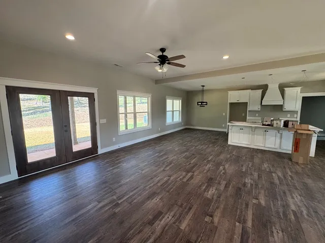a view of a big room with wooden floor a kitchen view and a window