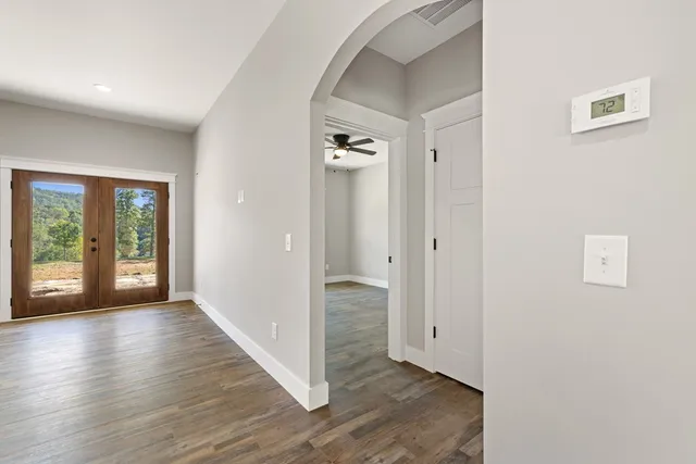 a view of an empty room with wooden floor and a window