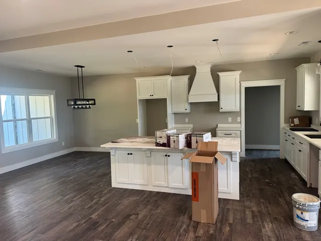 a kitchen with stainless steel appliances a stove a sink dishwasher a refrigerator and white cabinets with wooden floor