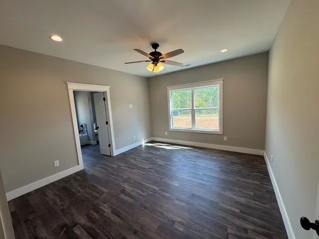 an empty room with wooden floor ceiling fan and windows