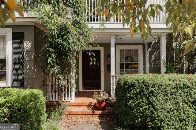 a view of a house with potted plants and a bench