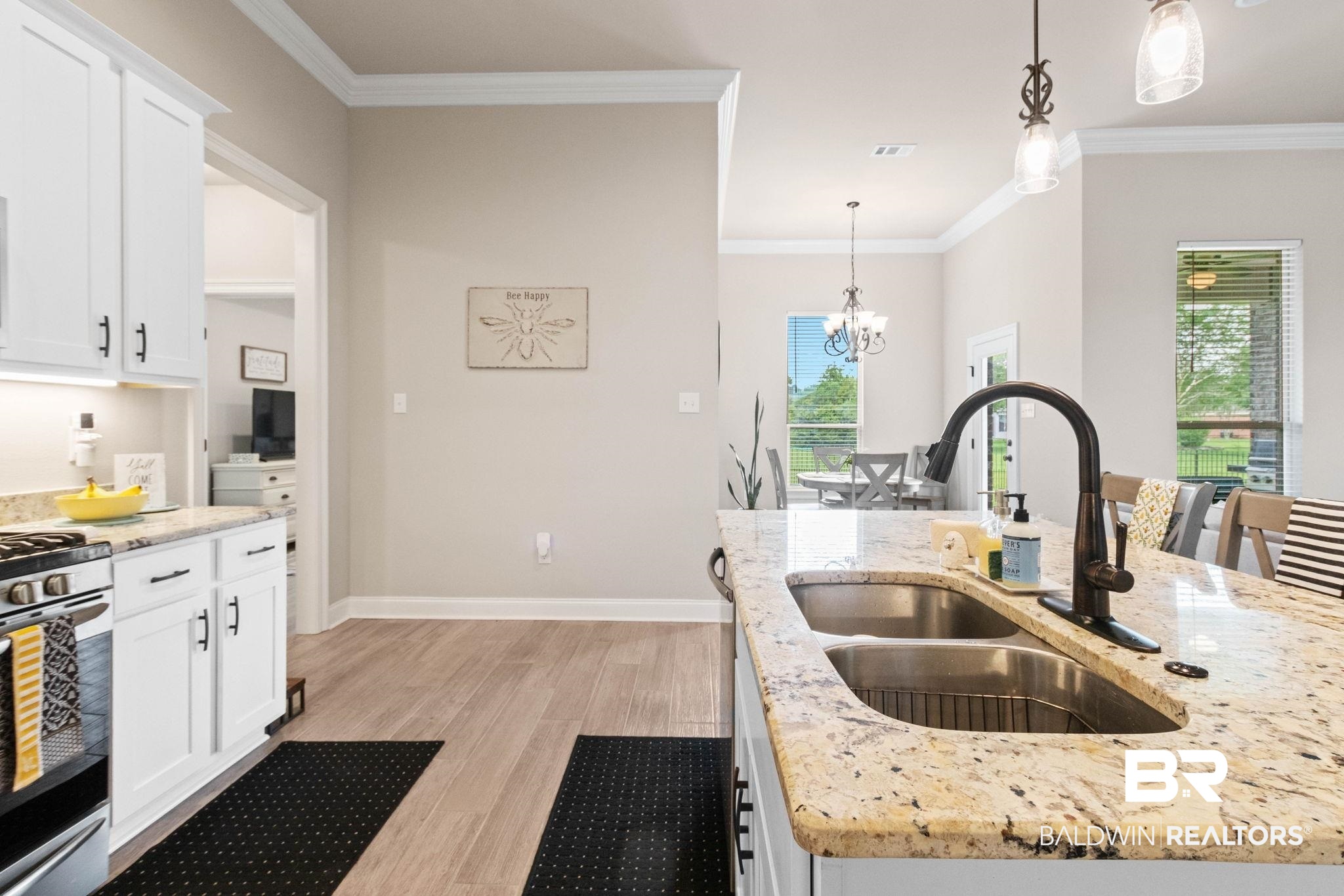 22244 Hibiscus Circle Foley, AL 36535 - Photo 29 of 51 Kitchen featuring a double basin sink with a gooseneck faucet, light-toned granite countertops, white cabinetry with dark hardware, and wood-finish flooring