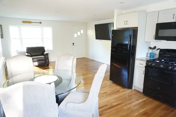a kitchen with stainless steel appliances kitchen island granite countertop a refrigerator a stove a sink dishwasher and white cabinets with wooden floor