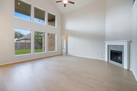 an empty room with wooden floor and ceiling fan