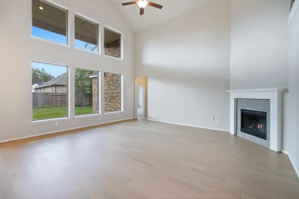 an empty room with chandelier fan and windows